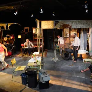 Escena de la obra, con el reparto en la escenografía.