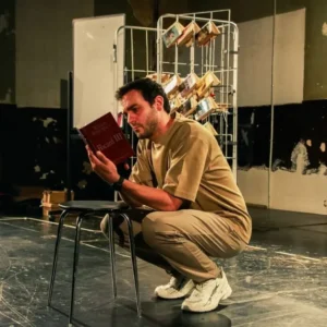 L'actor Quim Àvila en escena, assegut al terra, llegint un exemplar de 'Ricard III' de Shakespeare.